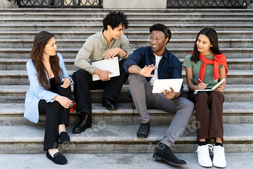 Preview: Group of students studying and collaborating on steps of university building