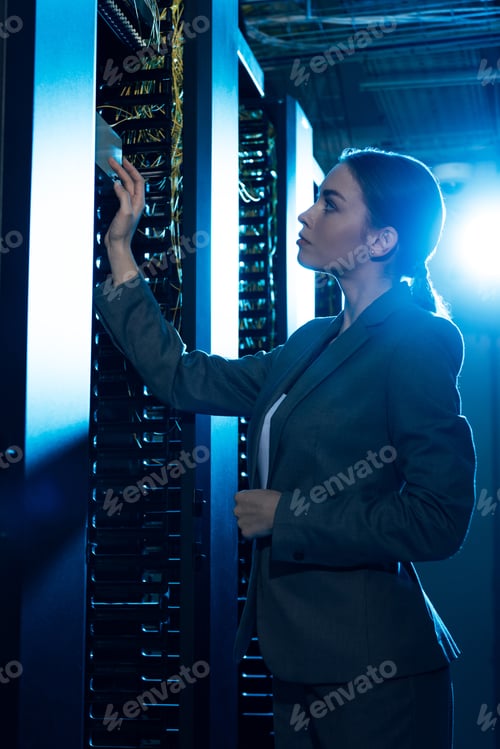 Preview: attractive businesswoman looking at server rack in data center
