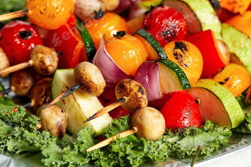 Preview: vegetarian skewers with dry herbs on wooden skewers of zucchini tomato onion mushrooms on a plate