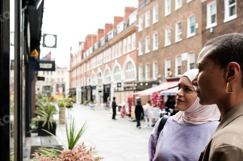 Preview: Two multiethnic women looking to a window shop in a London street.