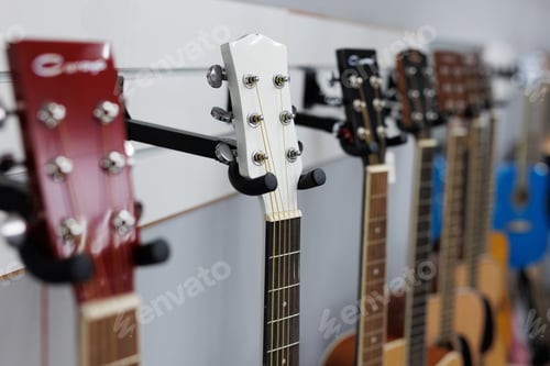 Preview: Close-up of the fingerboard of wooden guitars, ukulele on a guitar stand in the hall of music store.