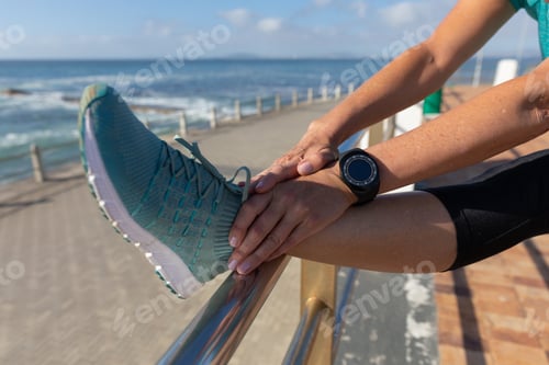 Preview: Female jogger stretching on seaside