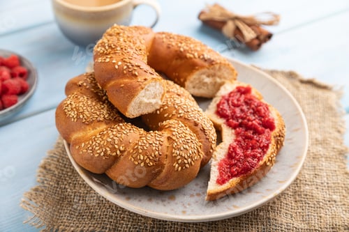 Preview: Homemade sweet bun with raspberry jam and cup of coffee on a blue wooden