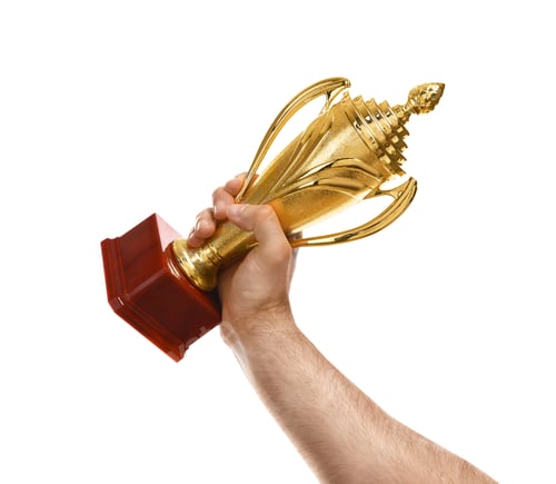 Preview: Young man holding gold trophy cup on white background, closeup