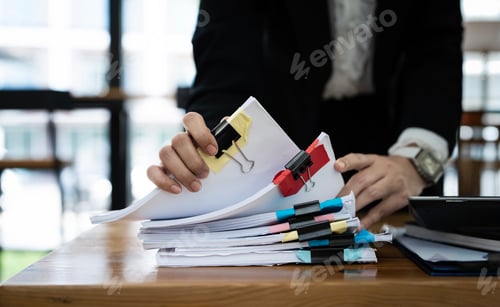 Preview: Businesswoman working in Stacks of paper files for checking unfinished document