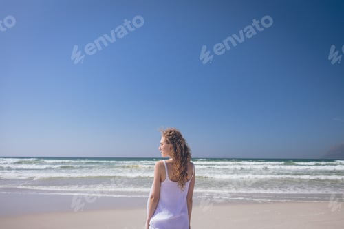 Preview: Rear view of beautiful Caucasian woman standing at beach on a sunny day