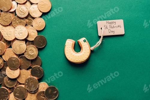 Preview: top view of icing cookie in shape of horseshoe and golden coins on green, st patricks day concept