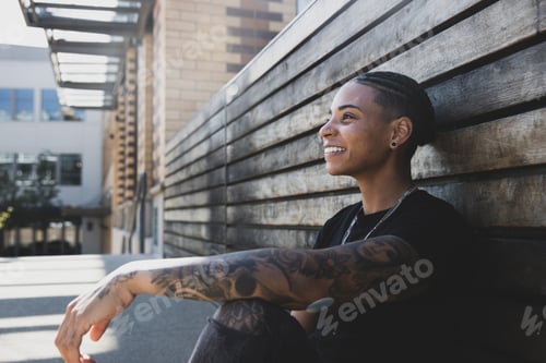 Preview: Young African American woman with tattoos on arm wearing black tee