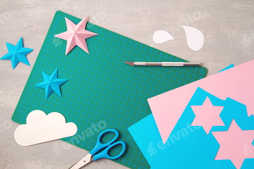 Preview: Top view over paper cut tools, scissors, cutter, cutting mat, and crafted paper objects. DIY trendy