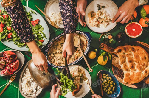 Preview: Flat-lay of people having Turkish dinner with lamb, rice, salad