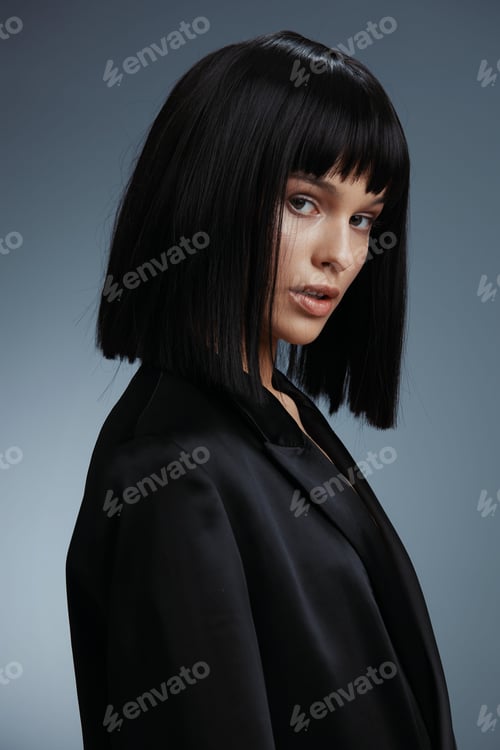 Preview: Blackhaired woman in a black suit jacket poses for the camera, gazing to the side