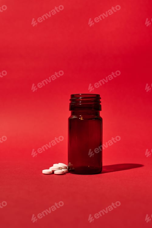 Preview: A pill bottle with medicinal pills on a red background. Isolated