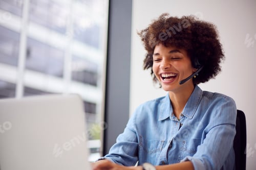 Preview: Young Businesswoman In Modern Office Working On Laptop Using Wireless Headset