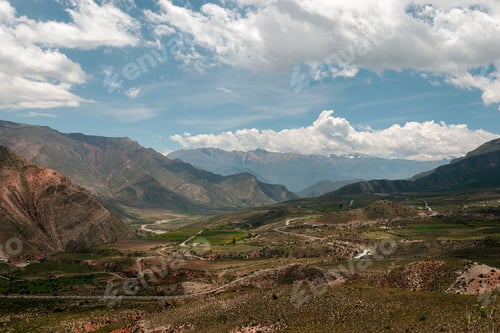 Preview: Stunning mountain valley landscape with fluffy clouds, lush greenery, and towering peaks