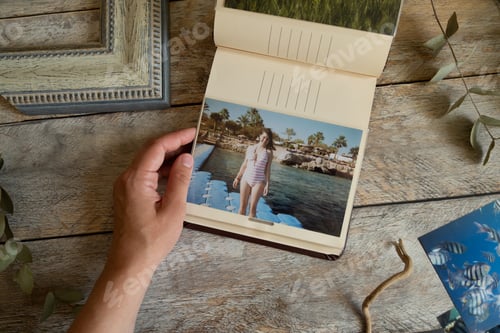 Preview: Woman browsing picture album with printed photos.