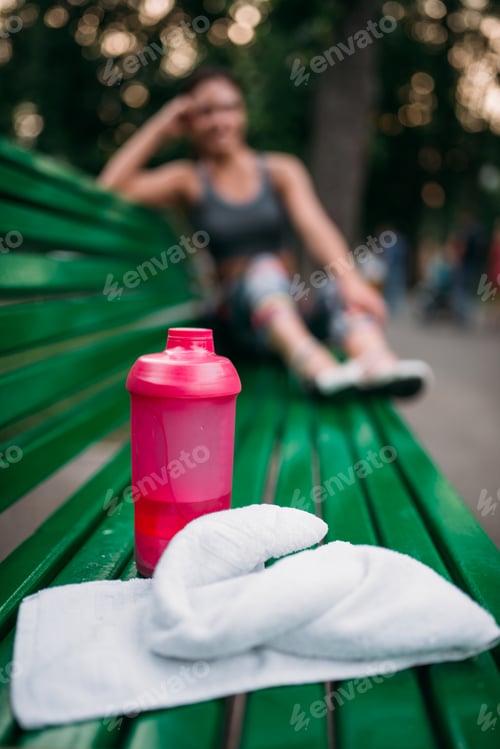 Preview: Sport bottle and towel on a bench in summer park