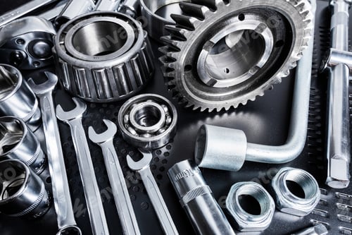 Preview: Tools and mechanical components arranged on a black surface with dramatic lighting highlighting the