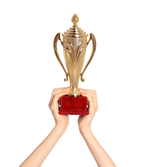 Preview: Young woman holding gold trophy cup on white background, closeup