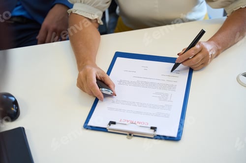 Preview: Buyer in the car dealership signs documents on the purchase of a car