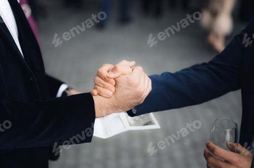 Preview: Two men shaking hands in a formal agreement.