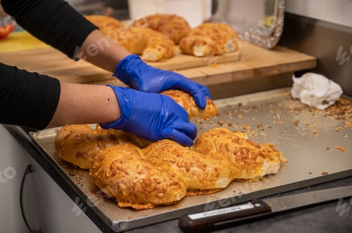 Preview: Selective focus shot of a woman making croissants in the kitchen with gloves and sharp knife
