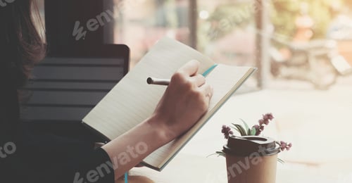 Preview: Business woman hand working at a computer and writing on a noteped with a pen in the office.