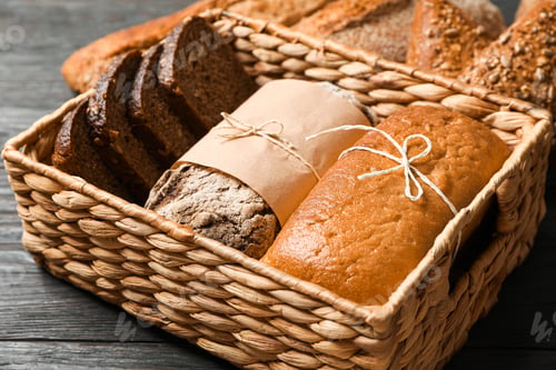 Preview: Bakery products in straw basket on wooden background, closeup and space for text