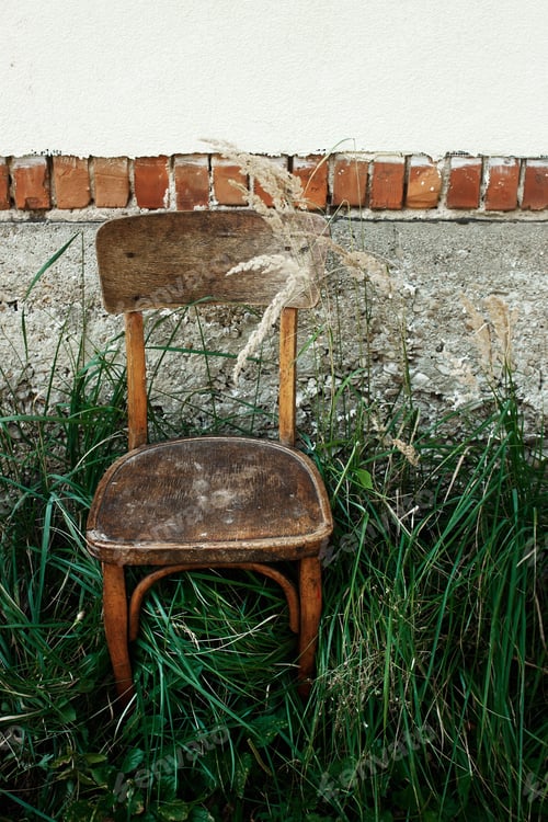Preview: old wooden chair and grass in backyard on background of aged house in village