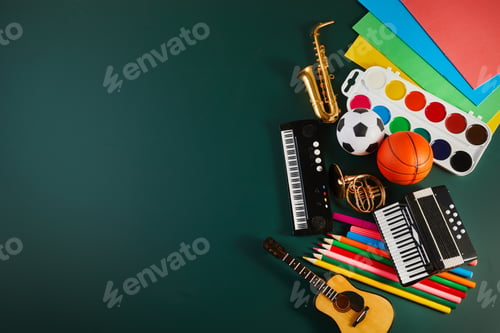 Preview: chool supplies on green chalkboard, flat lay with space for text.