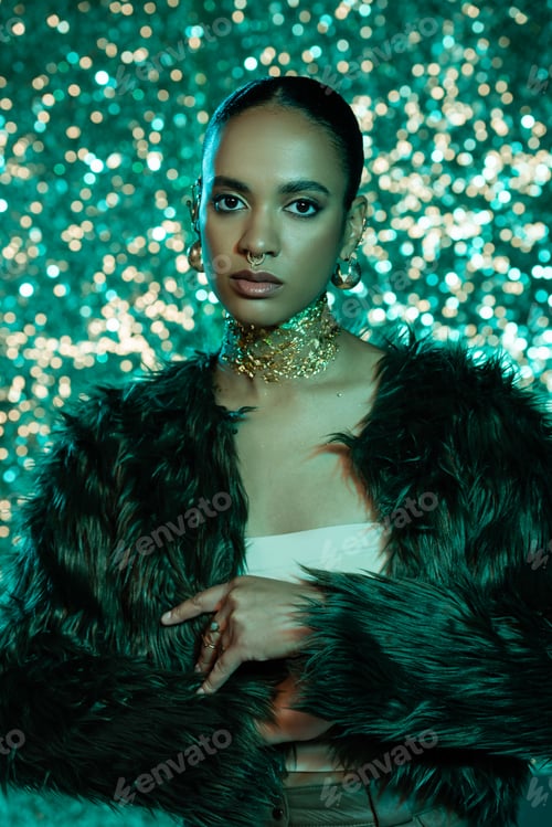 Preview: Fashionable african american woman in faux fur jacket and accessories looking at camera on sparkling