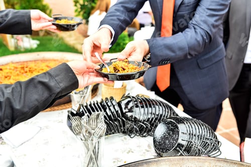 Preview: Cooks serving the typical Valencian paella during an event, traditional Spanish food.