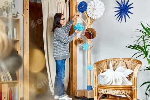 Preview: Woman decorating home with stars, fans and snowflakes made of recycled paper