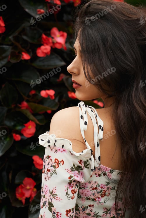 Preview: Attractive brunette woman in cute dress near flowers.