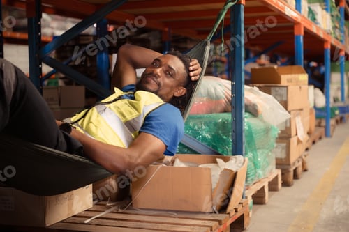 Preview: Portrait of happy mature African American man relaxing in hammock in warehouse