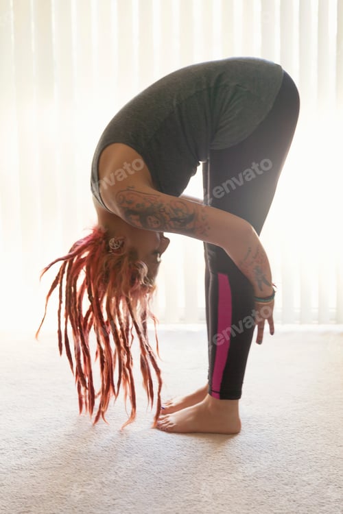 Vista previa: Young woman with pink dreadlocks practicing yoga in living room