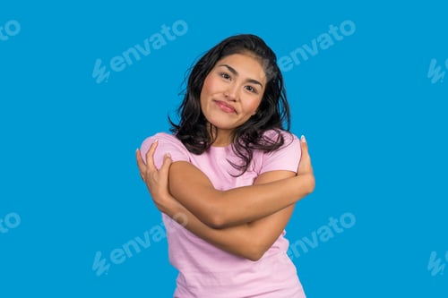 Preview: Young woman hugging herself on blue background