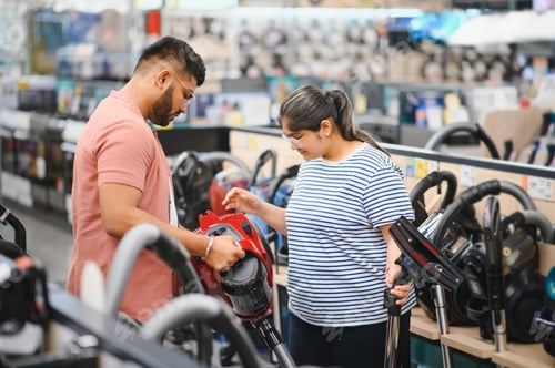 Preview: Young beautiful indian couple buying new vacuum cleaner at tech store