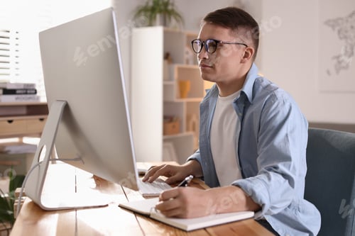 Preview: Handsome man working with computer at desk indoors. Home office