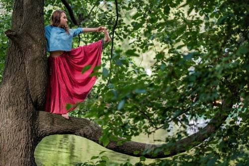 Preview: Caucasian woman standing in yoga balance Utthita Hasta Padangusthasana pose. She hold trank of tree