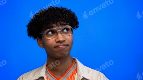 Preview: Pensive young african american man in eyeglasses looking away isolated on blue