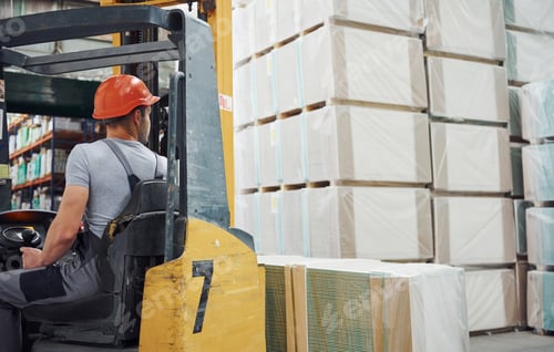 Preview: Young worker in unifrom sits in the forklift in the warehouse