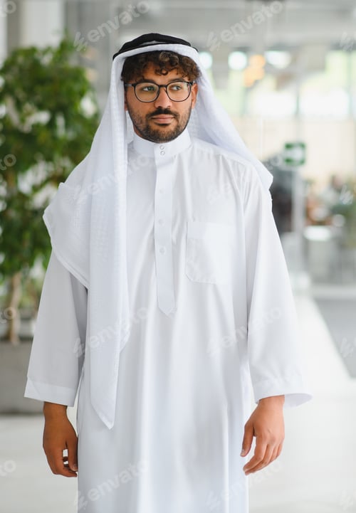Preview: Arab businessman wearing traditional kandura walking in modern office