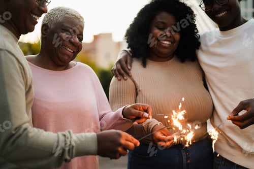 Preview: Happy african family celebrating with sparklers outdoor at home - Focus on mother face