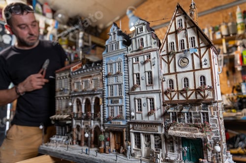 Preview: Model maker man working at scale model of miniature building in his workshop full of tools