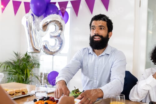 Preview: Man celebrating birthday at party with balloons and festive decorations indoors