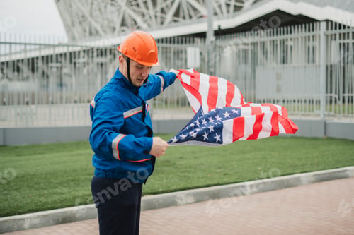 Preview: a patriontic american male worker holding usa national flag outdoors