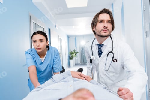 Preview: Serious doctors with stethoscope transporting patient on gurney