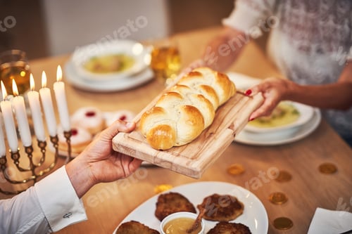Preview: Hanukkah dinner. Family gathered around the table sharing challah