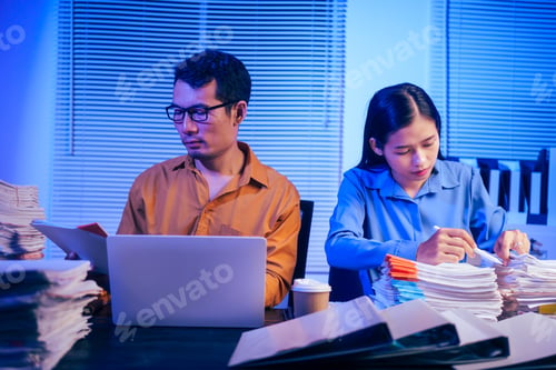 Preview: A businessman and woman are working overtime at their desks office at night.They are busy,stressed