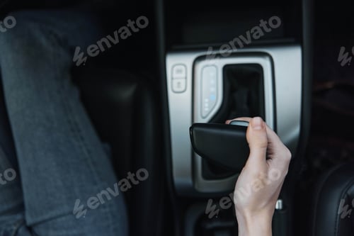 Preview: Driver's seat, modern car, hand holding remote control, vehicle in motion a person's hand holds a